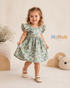 Vestido Helena – Menina girando com vestido floral e logo Nonoh Kids